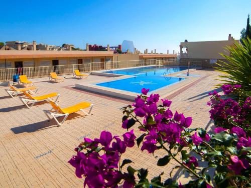 una piscina en la parte superior de un edificio con sillas y flores púrpuras en Apartment Cala Manzanera-2 by Interhome, en Calpe