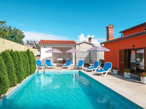 a swimming pool with blue chairs and umbrellas at Holiday Home Starci - LBN406 by Interhome in Labin