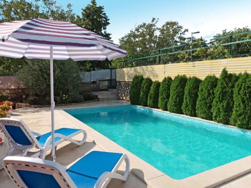 a swimming pool with two chairs and an umbrella at Holiday Home Starci - LBN406 by Interhome in Labin