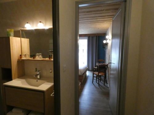 a bathroom with a sink and a kitchen with a table at Hôtel Du Midi in Thônes