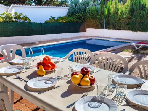 una mesa con platos y fruta junto a una piscina en Holiday Home Villa Santa Marta IV by Interhome, en Les tres Cales