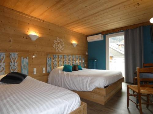 a bedroom with two beds and a wooden wall at Hôtel Du Midi in Thônes