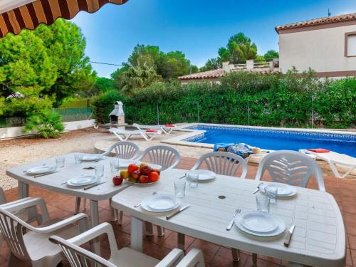 a table and chairs in front of a pool at Villa Mimosa II by Interhome in Les tres Cales