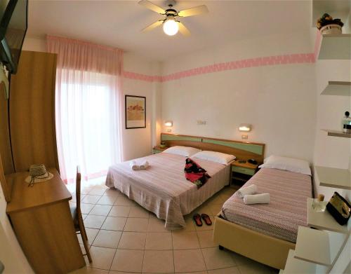 a bedroom with two beds and a ceiling fan at Hotel Holland in Rimini