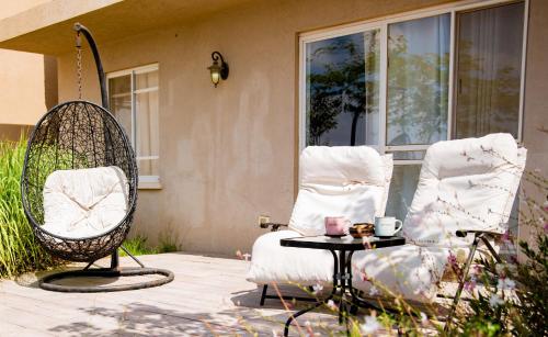 a patio with two chairs and a table and a swing at Desert View in Yeroẖam