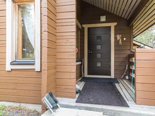 una casa in legno con una porta nera e una panchina di Holiday Home Tunturipöllö - huoneisto 902 by Interhome ad Äkäslompolo