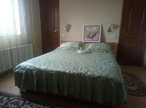 een slaapkamer met een bed met een groen dekbed bij Гостевой дом на Елисейских полях in Mykolaivka