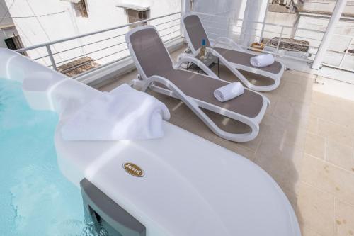 a group of chairs sitting on a balcony next to a swimming pool at Dama Bianca Boutique Hotel Ostuni in Ostuni