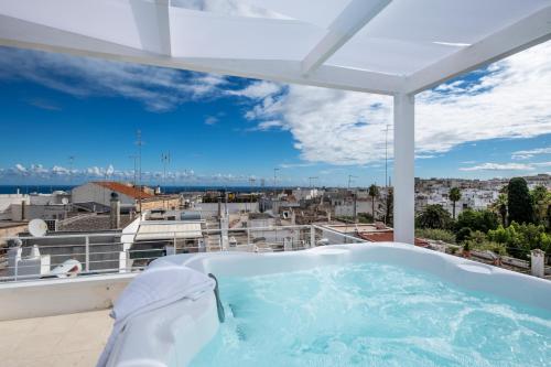 a hot tub on a balcony with a view of a city at Dama Bianca Boutique Hotel Ostuni in Ostuni