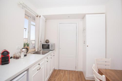a white kitchen with a sink and a microwave at Desert View in Yeroẖam