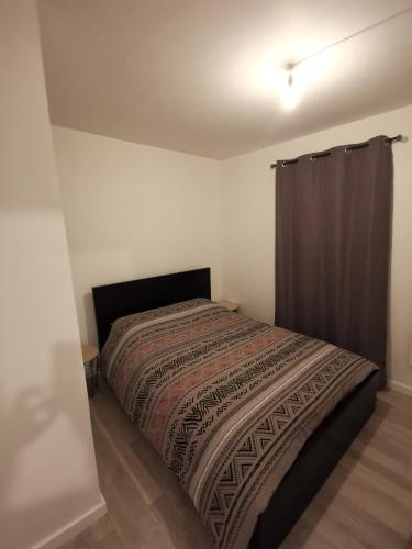 ein Schlafzimmer mit einem Bett mit einer Decke darauf in der Unterkunft Appartement Comfort in Grande-Synthe