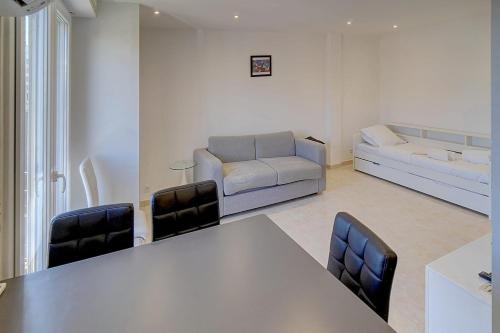 un salon avec une table, des chaises et un canapé dans l'établissement IMMOGROOM - Cozy - Cannes Center - AC in living room - Close to the sea, à Cannes