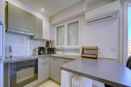 une cuisine avec des armoires blanches et un comptoir dans l'établissement IMMOGROOM - Cozy - Cannes Center - AC in living room - Close to the sea, à Cannes