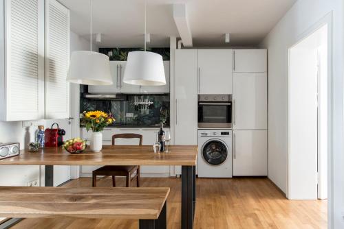 cocina con armarios blancos y mesa de madera en Mozart Apartment München, en Múnich