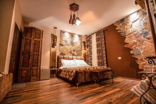 a bedroom with a bed and a stone wall at Vila Eden Boutique Hotel in Korçë