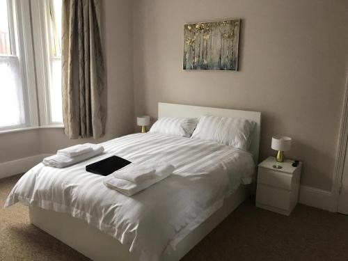 a bedroom with a white bed with a book on it at Poole Stay in Poole