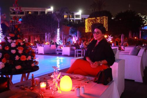 Mabrouk Hotel and Suites- Adult only في أغادير: امرأة تجلس على طاولة بجوار شجرة عيد الميلاد