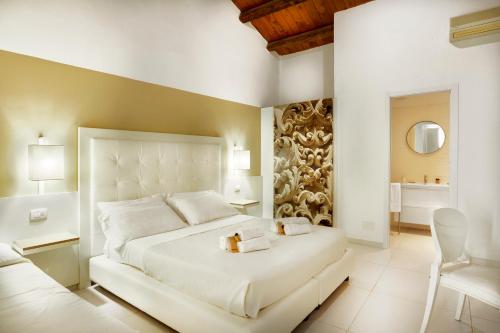 a bedroom with a large white bed and a chair at Villa Principe Di Belmonte in Ispica