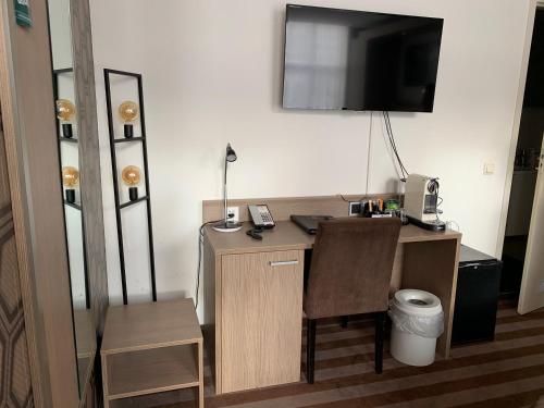 a desk with a chair and a television on a wall at Prinsengracht Hotel in Amsterdam