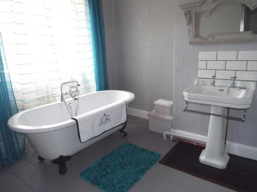 uma casa de banho com uma banheira branca e um lavatório. em Old Vicarage B&B em Coleford