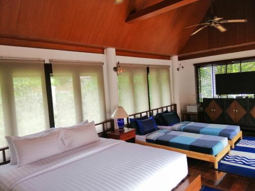 a bedroom with two beds and a flat screen tv at Casa Khaoyai Bed&Breakfast in Mu Si