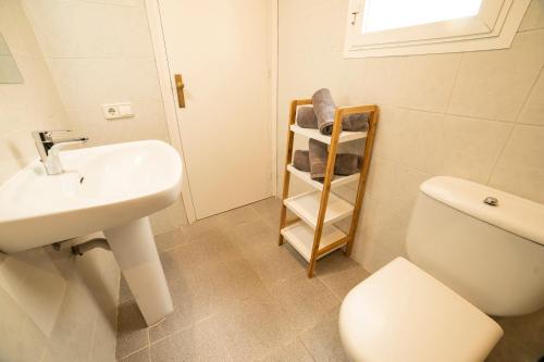 a bathroom with a sink and a toilet and a shelf at Apartaments Atzavara in Calella