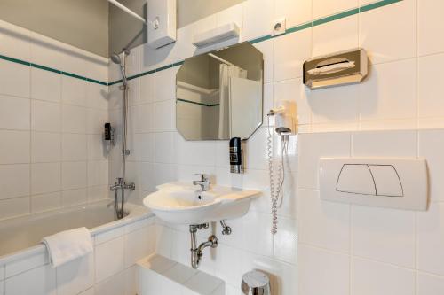 a white bathroom with a sink and a toilet at a&o Köln Hauptbahnhof in Cologne