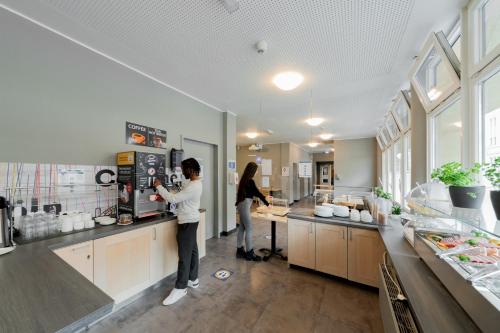 two people standing in a kitchen preparing food at a&o Köln Dom in Cologne