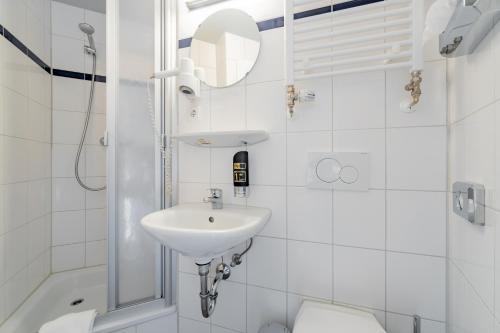 ein weißes Bad mit einem Waschbecken und einem WC in der Unterkunft a&o Köln Dom in Köln