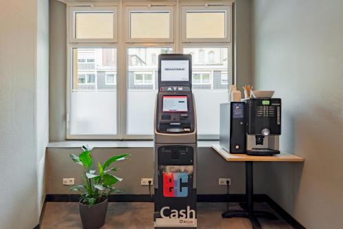 a cash machine sitting next to a table next to a window at a&o Köln Dom in Cologne