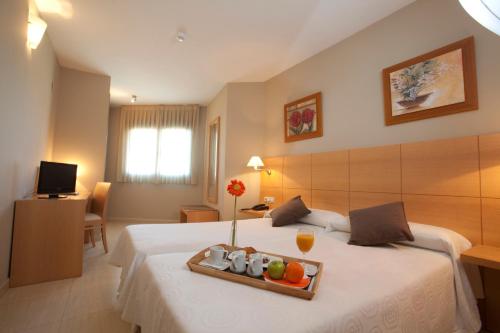 Habitación de hotel con cama y bandeja de fruta. en La City Estación, en Alicante