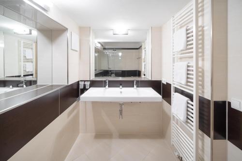 ein Badezimmer mit einem weißen Waschbecken und einem Spiegel in der Unterkunft Bohemia Apartments in Gargellen