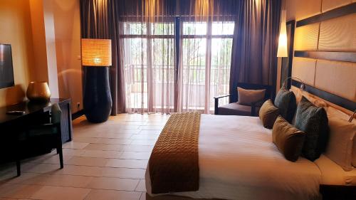 um quarto de hotel com uma cama grande e uma janela em Zimbali Heritage Place em Ballito