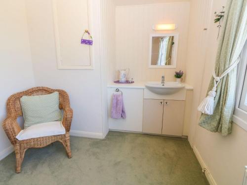 a bathroom with a wicker chair and a sink at Charming 2 Bed House near Rhoscolyn DISCOUNTS FOR in Holyhead