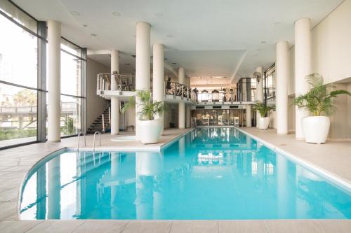 a pool in a hotel with blue water and plants at Citystay Apartments Century City in Cape Town