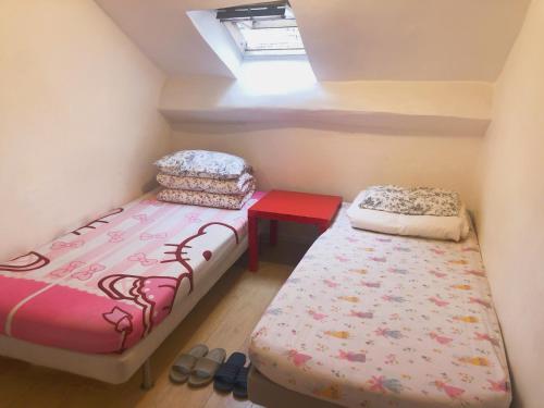Duas camas num pequeno quarto com uma janela em Art Beaubourg em Paris