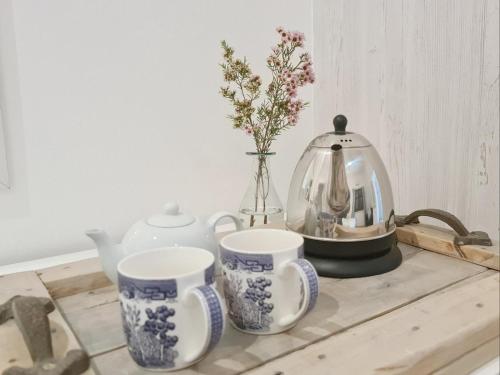 a table with two cups and a tea pot and flowers at Abbotts Hill in Malmesbury
