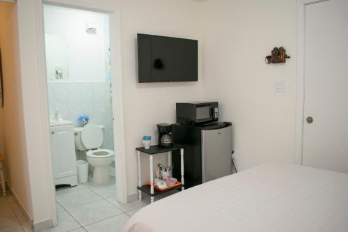 ein Schlafzimmer mit einem Bett, einem WC und einem TV in der Unterkunft Boho Studio in Little Havana - 5K in Miami