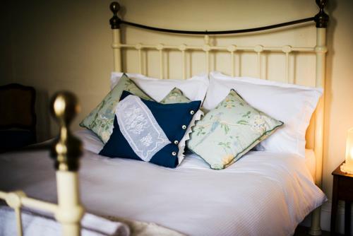 a bed with white pillows and blue pillows at Percy Place Bath in Bath