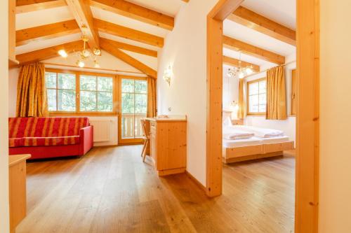 Großes Zimmer mit einem roten Sofa und einem Bett in der Unterkunft Residence Grüne Laterne - Lanterna Verde in Sexten
