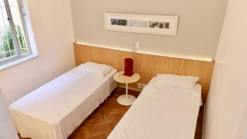 Cette petite chambre comprend deux lits et une table. dans l'établissement Ipanema Prudente Posto 9, à Rio de Janeiro