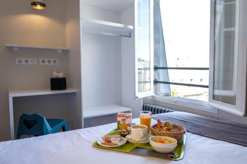 - un plateau de petit-déjeuner sur une table avec une fenêtre dans l'établissement HOTEL DE PARIS MONTPARNASSE, à Paris
