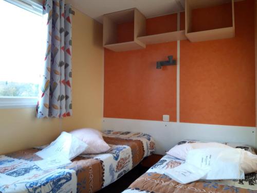 Ce lit se trouve dans un dortoir doté de murs orange et d'une fenêtre. dans l'établissement Camping de la Rive, à Notre-Dame-de-Monts