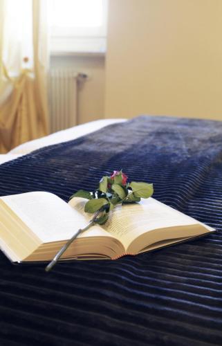 an open book with a flower on a bed at Antica Trattoria in Cles