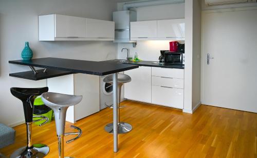 a kitchen with white cabinets and a black counter top at Hideaway Suite Danube Canal in Vienna