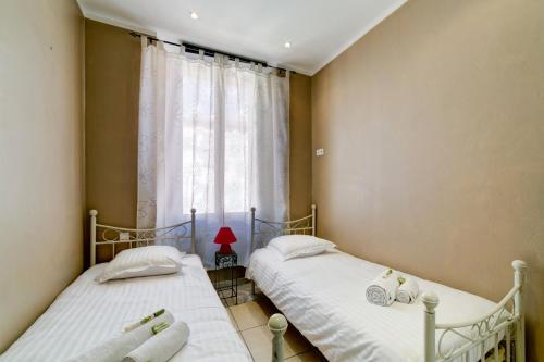 deux lits jumeaux dans une chambre avec fenêtre dans l'établissement IMMOGROOM - Historic Area Le Suquet - 6min from the beaches, à Cannes