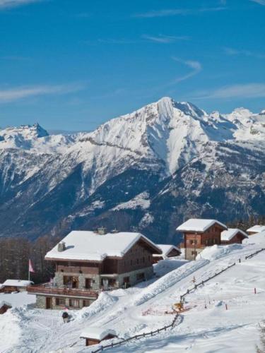 a snow covered mountain with a ski lodge in the foreground at Chalet des Alpes NATURE & MOUNTAIN by Alpvision Résidences in Prarion