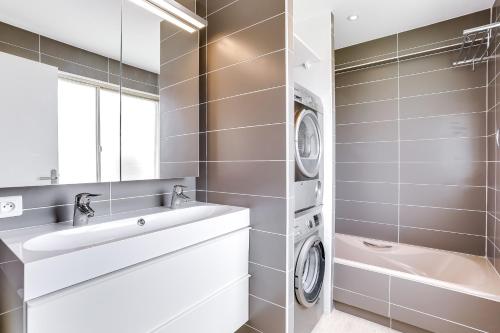 une salle de bain avec un lavabo et une machine à laver dans l'établissement IMMOGROOM - Apartment with terrace - AC - Parking, à Cannes
