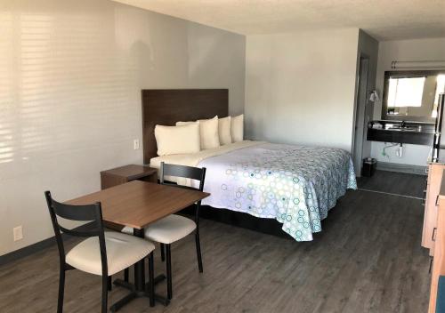 Una habitación de hotel con una cama, una mesa y sillas. en HomeTowne Studios by Red Roof San Antonio E - Frost Bank Center, en San Antonio