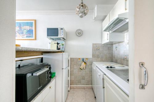 Elle comprend une petite cuisine avec des placards blancs et un réfrigérateur. dans l'établissement IMMOGROOM - Sea view - Swimming Pool - Terrace- Clim, à Cannes